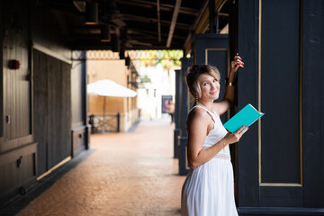 A beautiful woman in a white dress is reading a book