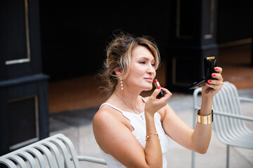 A beautiful woman applying lipstick, a close portrait