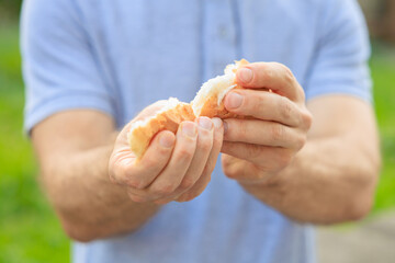 Guy's hand holds a round bun, snack and fast food concept. Selective focus on hands with blurred...