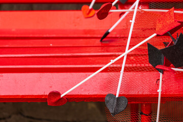 Cupid's arrows on a red wooden bench. Background with selective focus and copy space