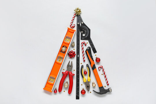Christmas tree made of construction tools and decorations on light background - Powered by Adobe