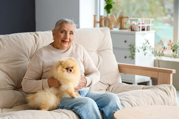 Senior woman with Pomeranian dog resting on sofa at home