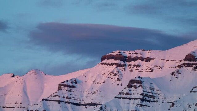 Timelapse of colorful sunset on the snowy mountain peaks in Utah looking at the saddle area of Timpanogos Mountain.