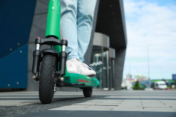 Man riding modern electric kick scooter on city street, closeup. Space for text