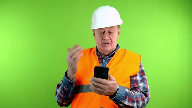 Builder in hardhat talking with phone webcam.