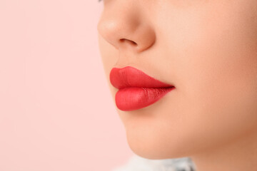 Beautiful young woman with red lipstick on pink background, closeup