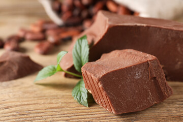 Pieces of tasty milk chocolate and mint on wooden table, closeup