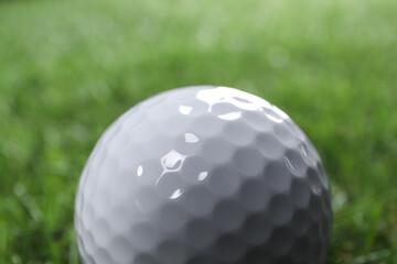 One golf ball on green background, closeup