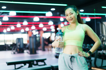Good looking - beautiful Asian woman relaxing in the gym after made weight training and cardio...