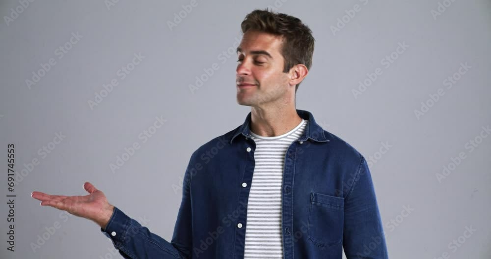 Poster face, smile and offer with the palm of a man in studio isolated on gray background to show space. po