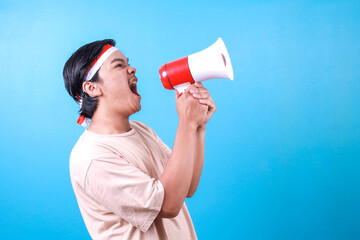 Side view of Asian guy wear headband and shouting in loudspeaker with excitement