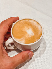 Cup of latte coffee in hand on white background surface