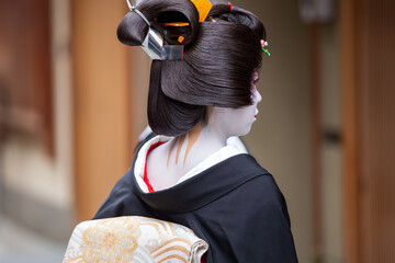 A traditional geisha out and about walking in Gion Kyoto Japan .