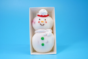 Daifuku snowman isolated on blue background. Snowman Daifuku, traditional Japanese dessert, Ideas for Christmas food, DIY, Do It Yourself. Greeting card for Christmas and New year, copy space for text