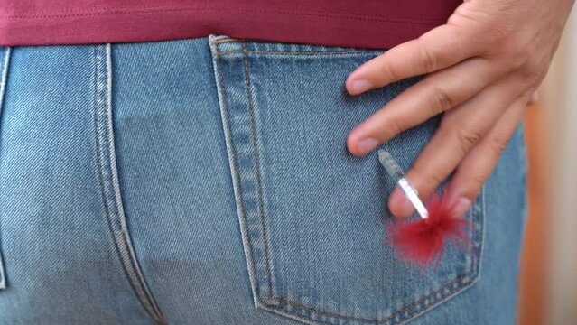Person shots in gluteal with small dart with sleeping pill causing sleep. Man removes dart with sleeping pill on tip from buttock dressed in jeans