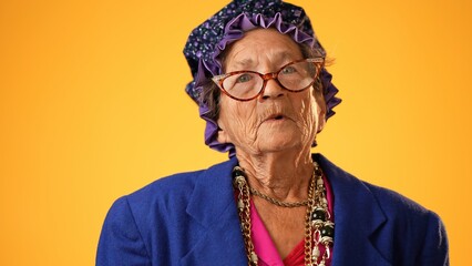 Closeup of funny happy smiling crazy grandmother mature woman, 80s, 90s, isolated on yellow background in studio