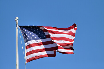 An American flag unfurls in the breeze on a flagpole at in a Chicago suburban community. The flag...