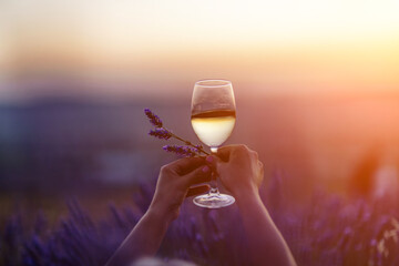 Glass white wine lavender field. Woman hand holds a glass with lavander and wine in the Lavender...