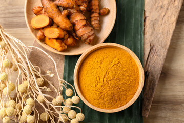 Turmeric powder and fresh turmeric in wooden bowl, Spice in Asian cuisine, Table top view
