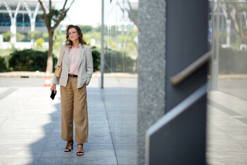 Portrait of stylish successful businesswoman standing in the street