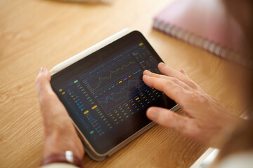 Closeup image of businesswoman analyzing trading data on tablet screen