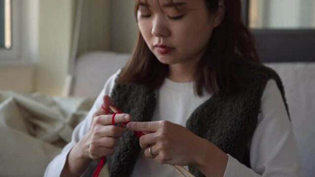 動画を観ながら編み物をする女性