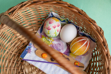 cesta con huevos de pascua decorados y uno sin decorar - obrazy, fototapety, plakaty