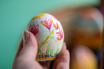 mano de mujer sosteniendo huevo cocido decorado como huevo de pascua con flores
