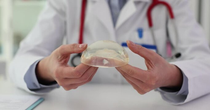 Plastic surgery silicone female breast implant in hands of doctor
