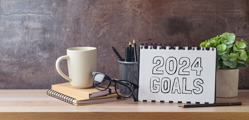 New Year 2024 goals and resolution business concept with notebook, coffee cup and plant on modern office table