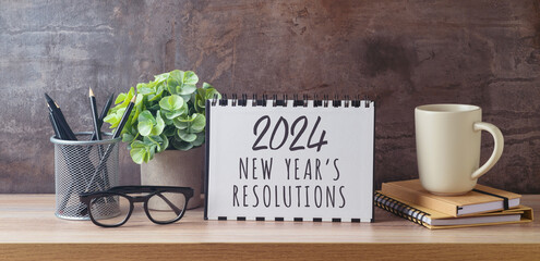 New Year 2024 goals and resolution business concept with notebook, coffee cup and plant on modern...