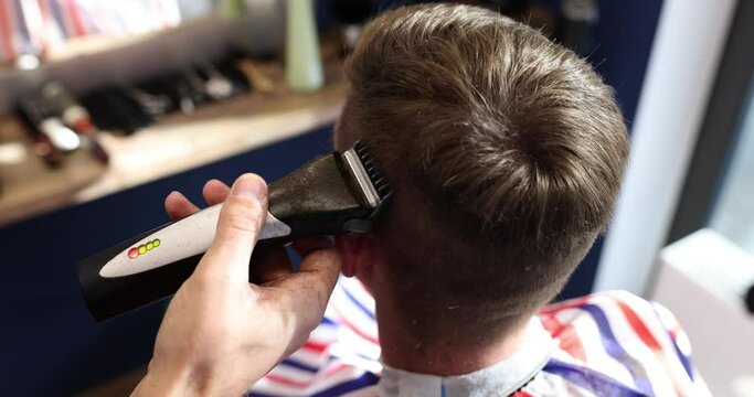 Hairdresser cuts man hair with clipper in barbershop