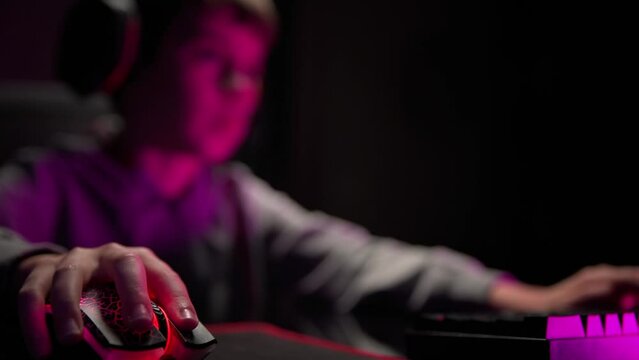 Teenager boy plays computer video game in dark room, cybersport gaming, children gaming addiction