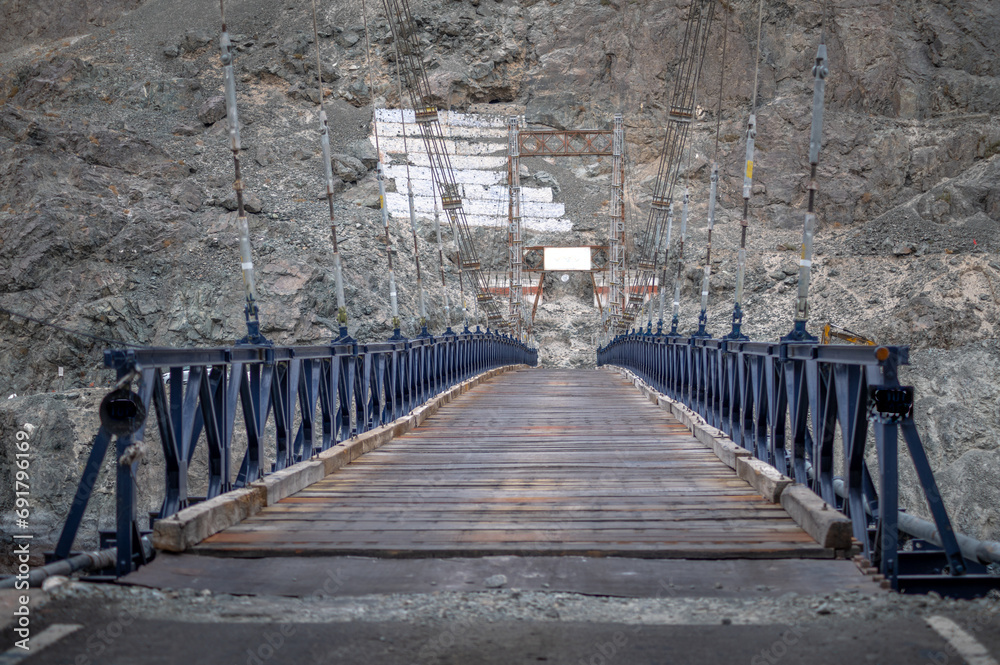 Wall mural the suspension bridge crossing the river in ladakh, india. rustic metal bridge image. bridge surroun