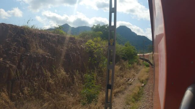 3rd December, 2023, Singapore Road, Orisa, India: A yellow long Indian railway diesel locomotive passenger train in countryside of dooars area on curvy stretch of track with selective focus.