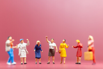 Naklejka premium Miniature people , A group of women stand together On a pink backdrop, International Women's Day concept