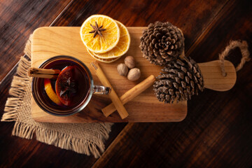 Fototapeta na wymiar Spiced wine or Christmas mulled wine with orange, cinnamon, star anise, clove, nutmeg and other ingredients on a wooden rustic table. Traditional hot drink at winter time and Christmas holidays.