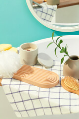 A domed wooden platform, a bath sponge, a jar of scented candles, a detangling comb and tree branches inside a ceramic jar are displayed. Bathroom space for advertising.