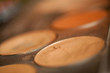 This image offers a close-up view of a makeup foundation palette with an array of skin-toned powders. The shallow depth of field puts the emphasis on the textures and colors of the makeup, from creamy