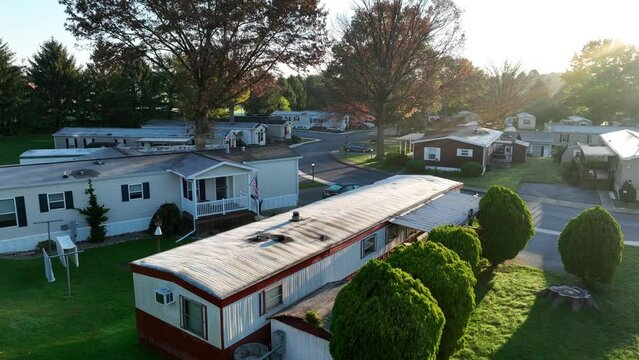 Sunlit mobile home park. Aerial view of manufactured houses with American flags.