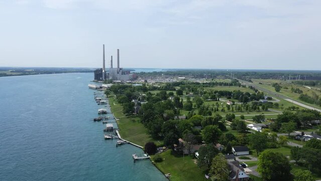 Private luxury estates with green gardens and massive power plant in background, aerial view