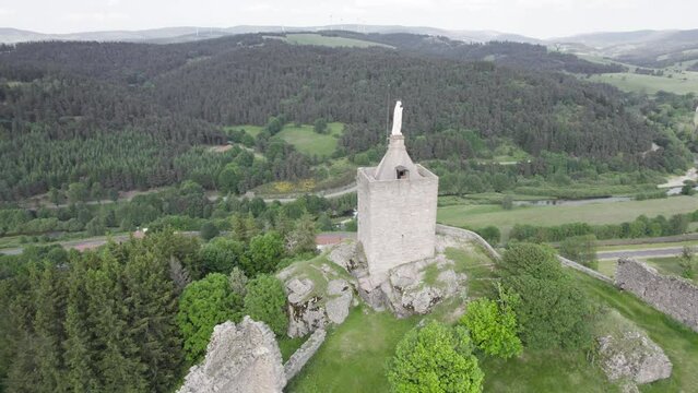 Chateau de Luc - Ruined Castle In Luc, Lozere, France With Virgin Mary Statue On Top. aerial orbiting shot