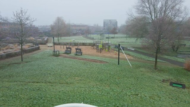 Low aerial of urban basketbal court towards a children playground on a cold and misty morning