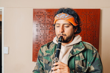 Alternative young latin male clarinetist playing at home