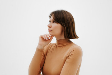 Portrait of a pensive confident adult Caucasian woman standing on a white background and looking away, side view
