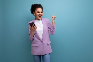 young latin business woman with a ponytail hairstyle dressed in a purple jacket uses a smartphone...