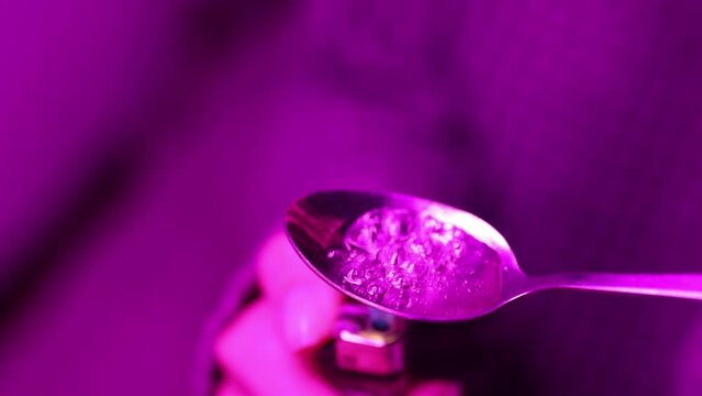 woman suffers from drug addiction withdrawal syndrome, preparing drugs with a lighter on a spoon.