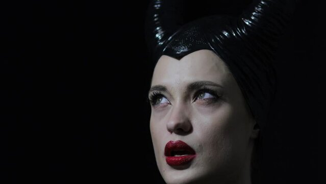emotional beautiful woman in the dark in a halloween costume, witch and actress with horns.
