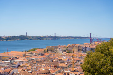 Fototapeta na wymiar Aerial View of Lisbon, Portugal: A High-Angle, Daytime Capture of the Cityscape, Featuring the Iconic 25 de Abril Bridge Spanning the Tagus River, with a Clear, Blue Sky