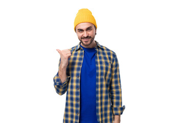young caucasian brunette handsome man with a beard and mustache points his hand to the side on a white background with copy space